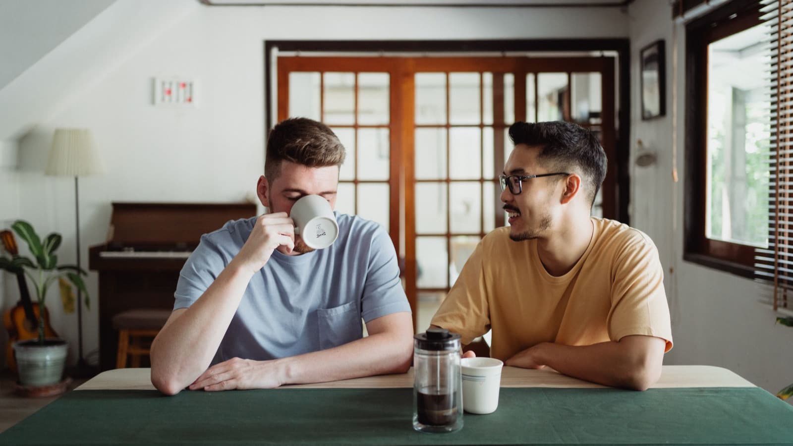Dois amigos conversando com café em casa, sentados lado a lado