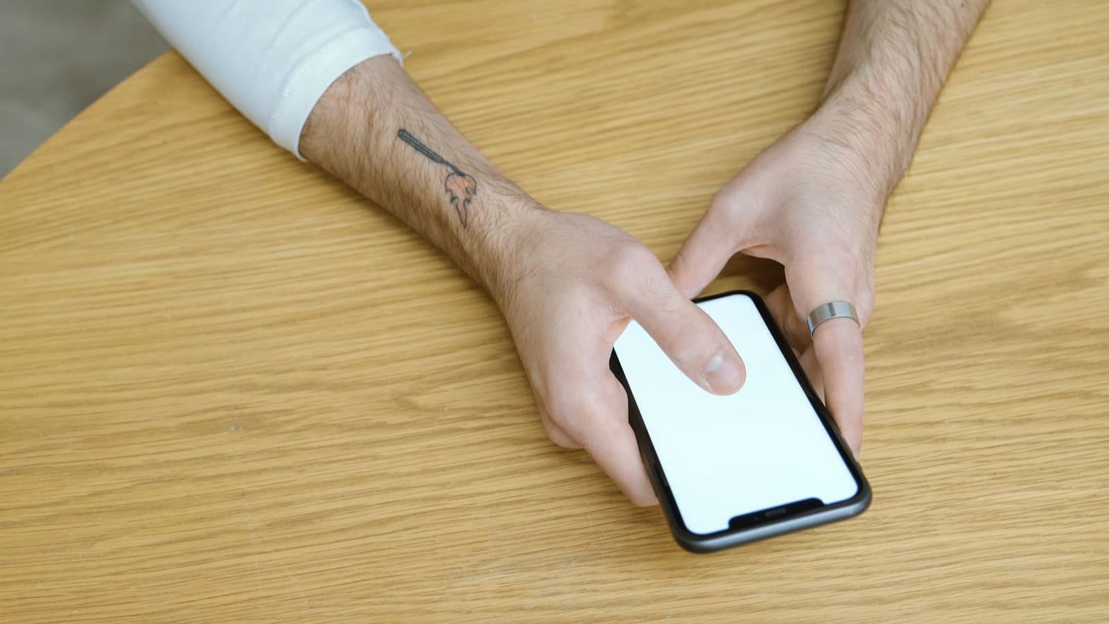 Mão pousando um celular sobre a mesa de madeira, fazendo uma pausa