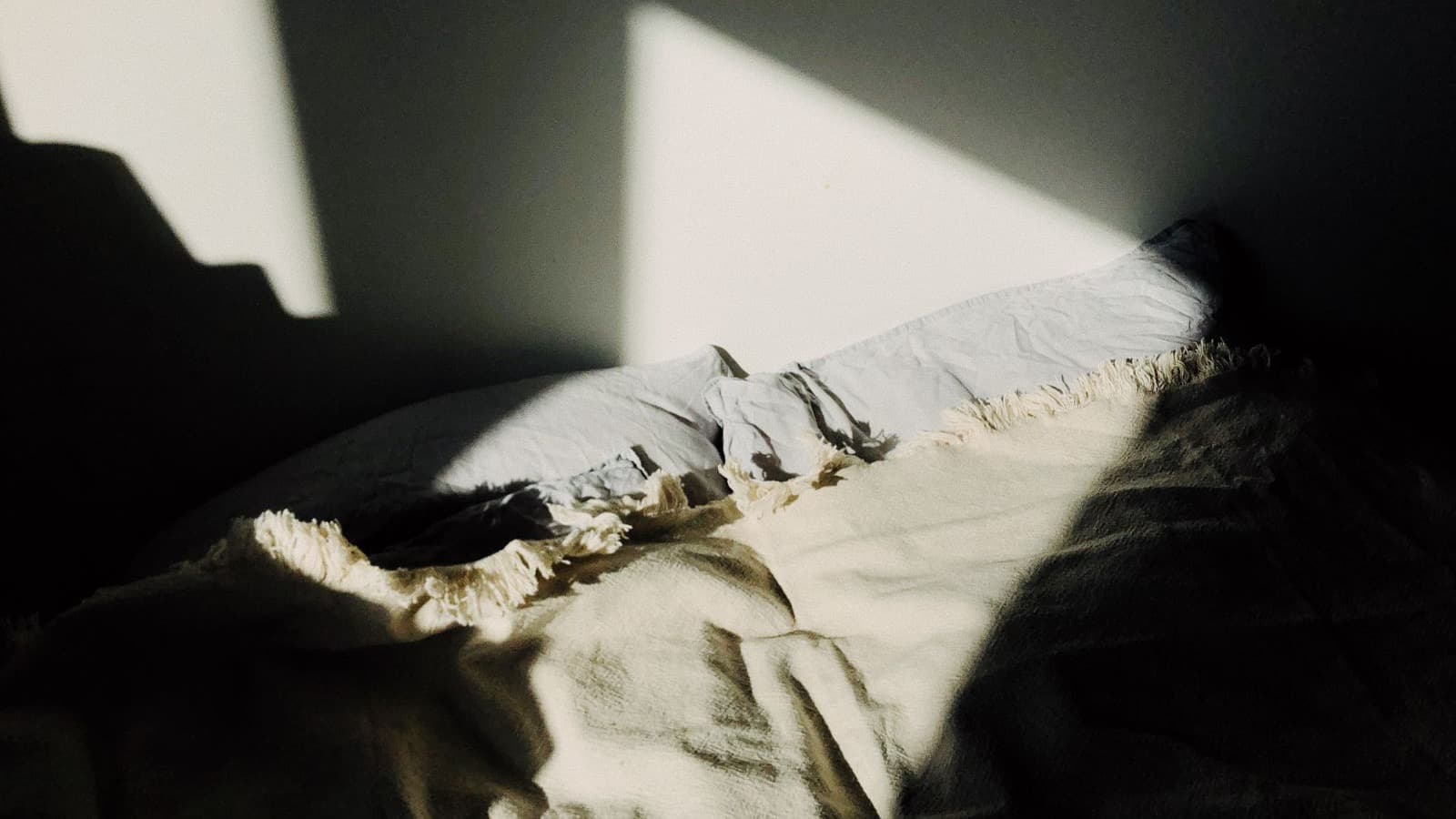 Travesseiro em uma cama serena, banhado por um feixe de luz quente